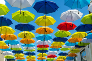 Lukuisia värikkäitä sateenvarjoja aurinkoisella taivaalla