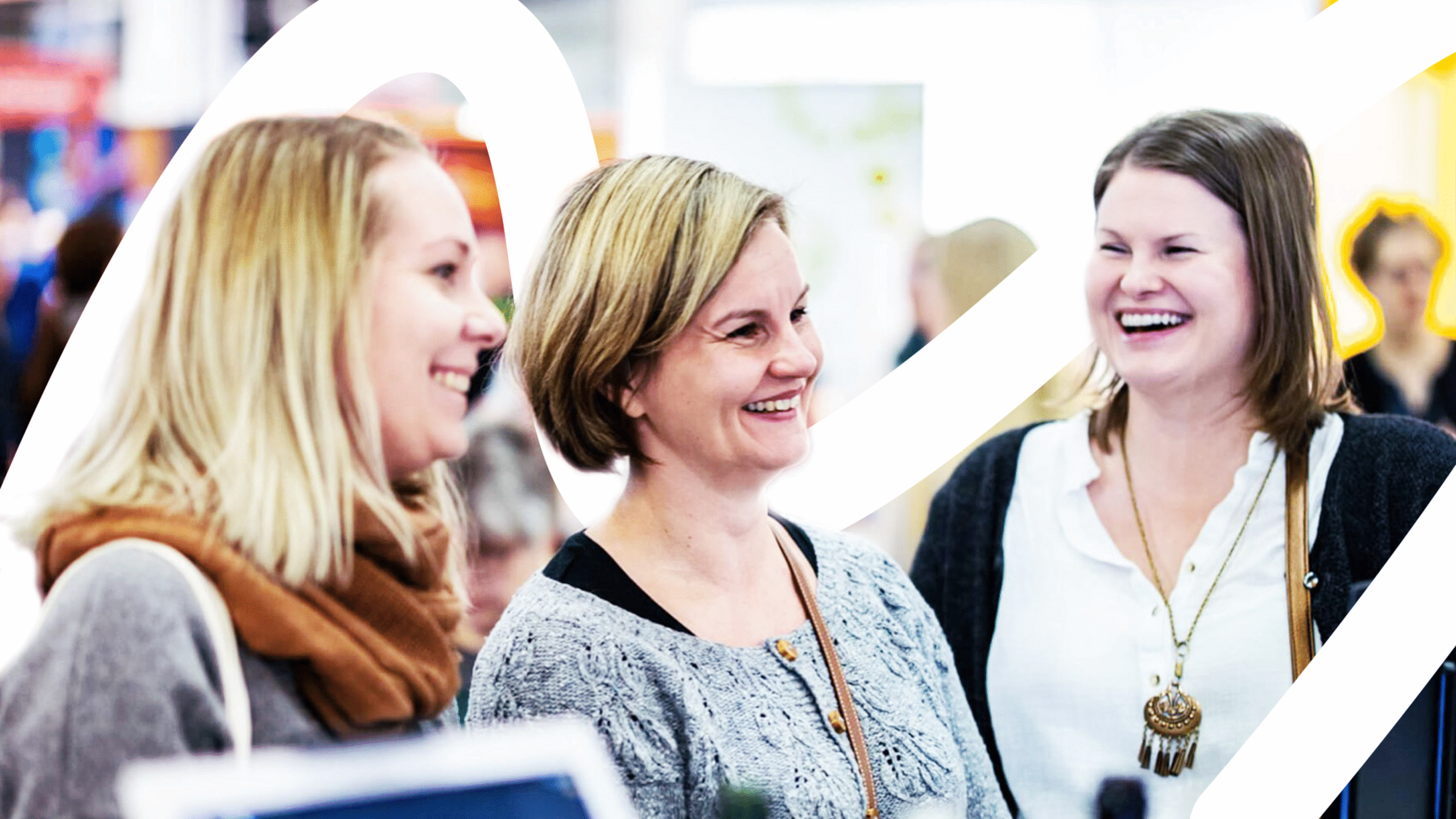 Kolme naista nauraa iloisesti katsellen oikealle kuvan ulkopuolelle